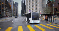 An autonomous mover stops at a bus stop in a multi-lane city street.
