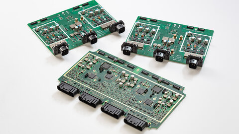 Three circuit boards, two of which are the same, lie diagonally, offset next to each other.