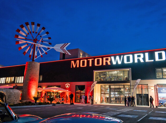 Mallorca location. The parking lot and the entrance to Motorworld Mallorca at night, with lots of red and white lights.