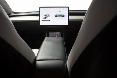 Looking forward from the back seat of a car toward the cockpit, you see a large touchscreen display in the middle, but no steering wheel.  