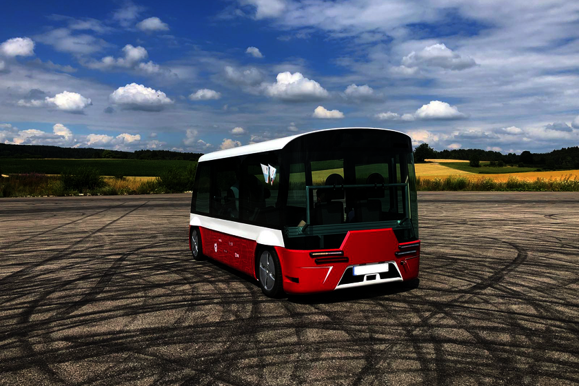 A red/white and black public transport bus is parked in a large square, behind which there are green meadows and sunflowers. You can look through the windshield and see that there is no steering wheel and no driver.