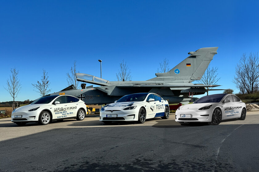 Three different Tesla vehicles are parked at an angle in front of a tornado against a blue sky. All are white with printing.