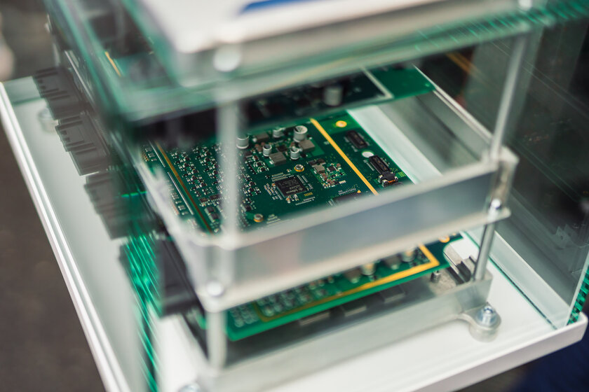 Behind a light green glass box, several circuit boards are displayed on top of each other as a structure. The whole thing is the content of an NX NextMotion.