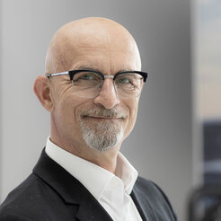 A friendly, smiling, bald man with glasses who is Mathias Koch and is your contact person.