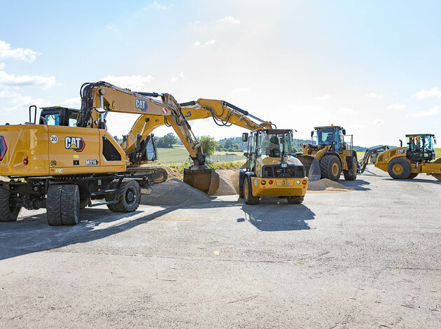 Caterpillar construction machines such as excavators, wheel loaders, and rollers in use on a sunny open construction site.