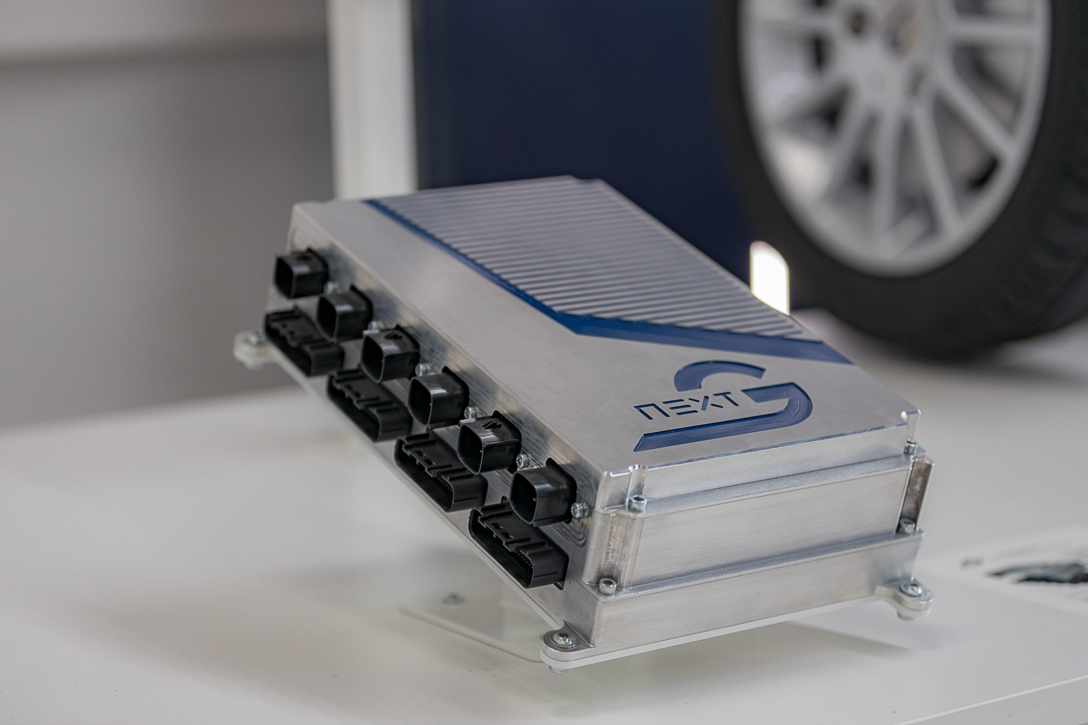 On a table sits the NX NextMotion control unit, which is displayed on a stand that tilts the NXM at an angle.